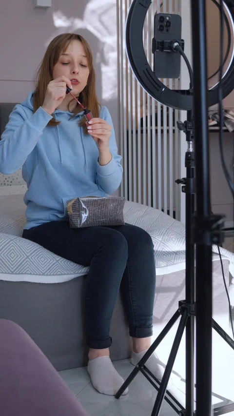 Beauty influencer applying lipstick while recording makeup tutorial Stock Footage 314525653