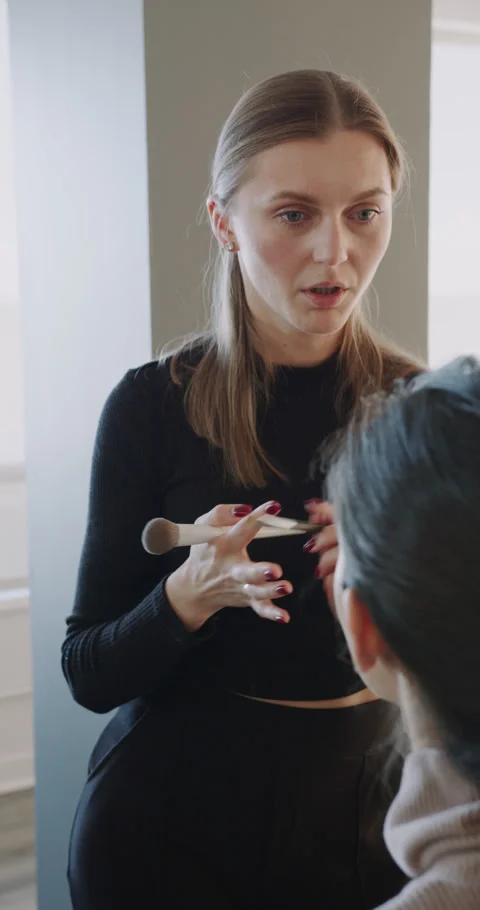 Beauty lesson exchange, Makeup instructor demonstrates techniques amidst bright Video stock 321037817