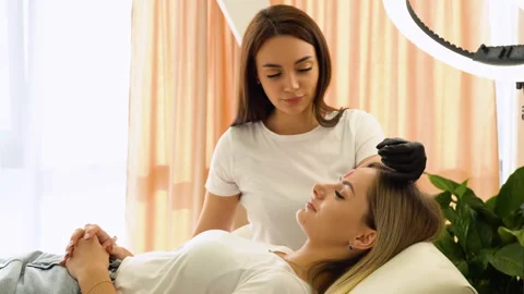 Beauty master brushing client's brows after permanent makeup procedure Stock Footage 255288917