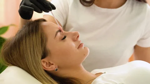 Beauty master brushing client's brows after permanent makeup procedure. Closeup Stock Footage 255289222