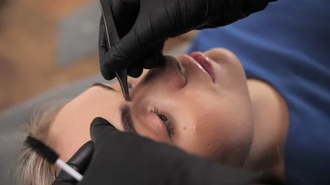 Beauty master performs eyebrow correction procedure for a young woman. Stock Footage 198881150