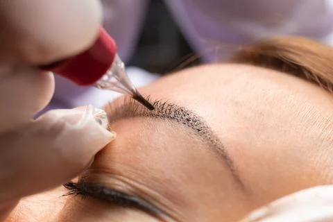 Beauty master performs permanent eyebrow makeup in a beauty salon, microbla.. Stock Photos