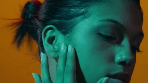 Beauty model in cyan gel light slides fingers up cheek Stock-Footage 337133873