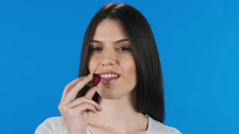 Beauty model posing on camera with red strawberry on blue background. Stock Footage 140582326