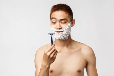 Beauty, people and hygiene concept. Curious handsome asian man looking at new Stock Photos