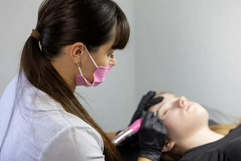 Beauty professional performs microblading procedure on client in modern studio Stock Photos