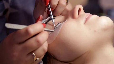 In the beauty salon the make-up artist increases eyelashes to the girl. Close-up Stock Footage