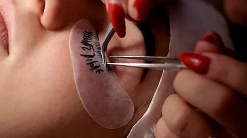 In the beauty salon the make-up artist increases eyelashes to the girl. Close-up Stock Footage