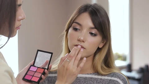 In the beauty salon make-up master puts a young woman . Stock Footage 93379758