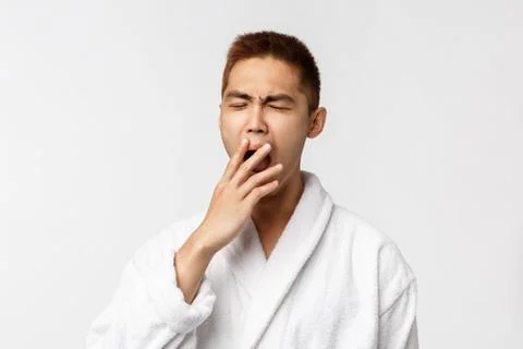 Beauty, spa and leisure concept. Portrait of young asian sleepy man, yawning and Stock Photos