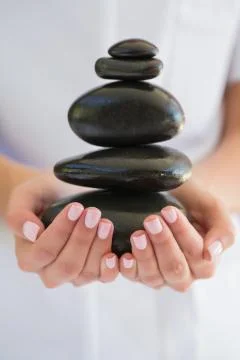 Beauty therapist holding pile of stones for massage Stock Photos
