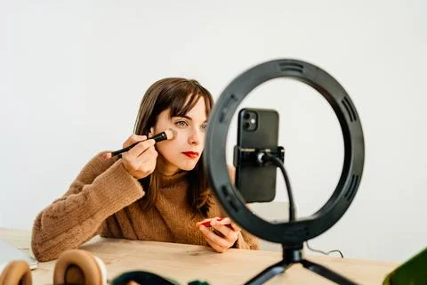 Beauty vlogger doing makeup tutorial at table Stock Photos