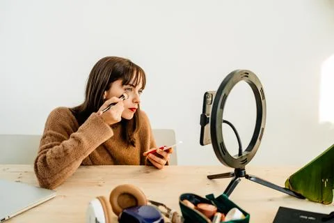 Beauty vlogger doing makeup tutorial at table Stock Photos