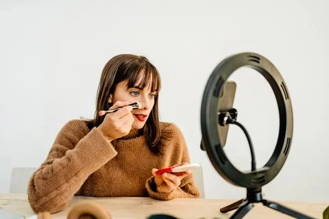 Beauty vlogger doing makeup tutorial at table Stock Photos