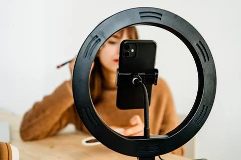 Beauty vlogger doing makeup tutorial at table Stock Photos