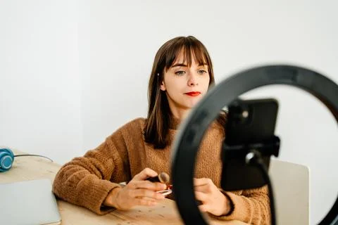 Beauty vlogger doing makeup tutorial at table Stock Photos