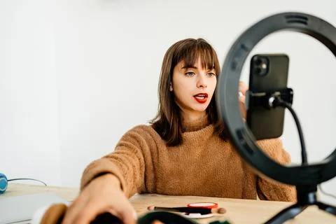 Beauty vlogger doing makeup tutorial at table Stock Photos