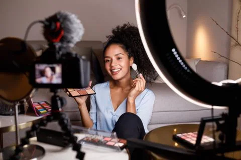 Beauty vlogger making a video tutorial on makeup in living room Foto stock