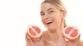 The beauty woman holding two halves of a grapefruit on the white background 4k or 4k+ Resolution