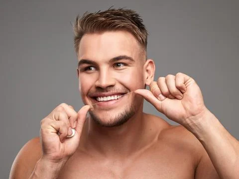 Because bacteria is so basic. Studio shot of a handsome young man flossing his Photos