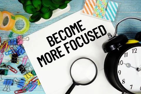 Become More Focused text on a paper surrounded by office supplies, a magnif.. Stock Photos