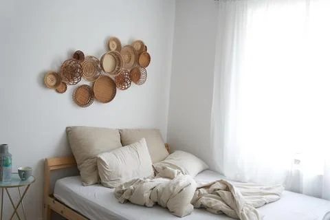 The bed is at the back of the room. The bed is not made. Beige color. The decor Fotos de archivo