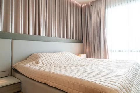 Bed with bedspread in bedroom Stock Photos