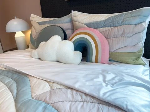 Bed with decorative rainbow and cloud pillows Stock Photos