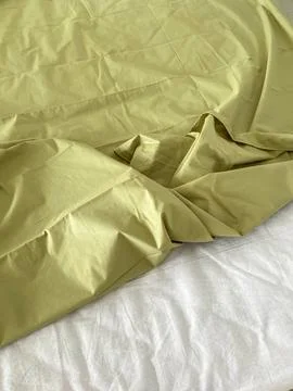 Bed linen is arranged on a mattress with a solid light green color and a wh.. 스톡 사진