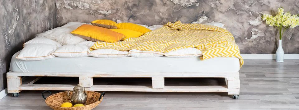 Bed made of pallets in loft interior. Stock Photos