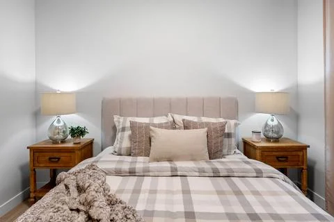 The bed is made with a white comforter and a plaid pattern Stock Photos