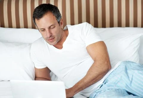 Bed, man and scroll on laptop in morning for reading global news, market tr.. Stock-Fotos