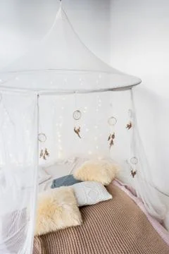 Bed with patterned bedding and white drapes in bright bedroom interior.Cozy Foto stock