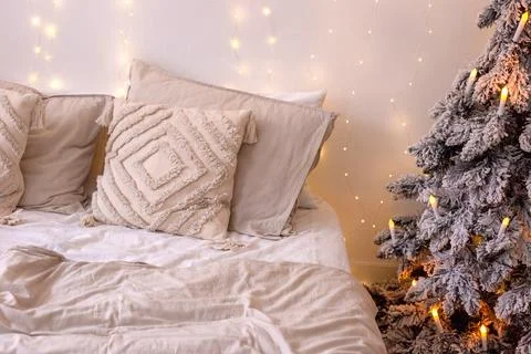 A bed with pillows and a beige bedspread, next to a snow-covered artificial Stock Photos