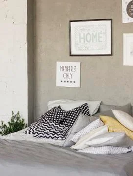 Bed with pillows in room in the loft. Concrete walls, posters. Scandinavian i Stock Photos