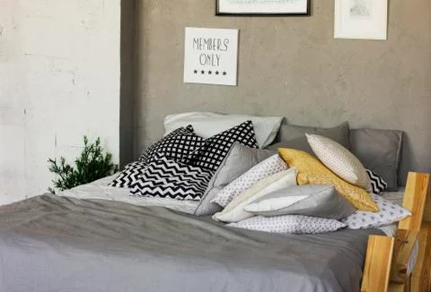 Bed with pillows in a room in the loft. Concrete walls, posters. Scandinavian Stock Photos