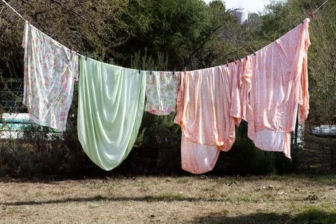 Bed sheets hanging from a clothes line in a garden Foto stock