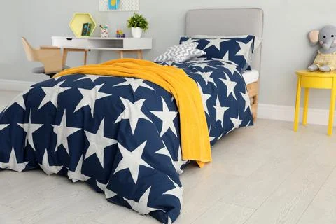Bed with star patterned linens in child's bedroom. Interior design Stock Photos