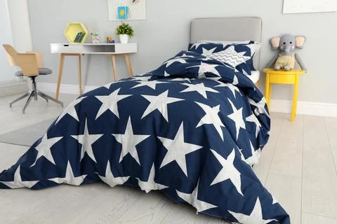 Bed with star patterned linens in child's bedroom. Interior design Stock Photos