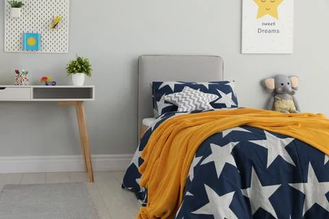 Bed with star patterned linens in child's bedroom. Interior design Stock Photos