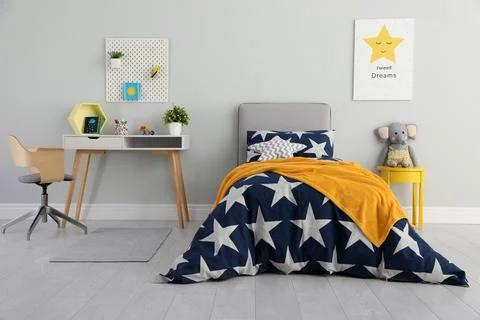 Bed with star patterned linens in child's bedroom. Interior design Stock Photos