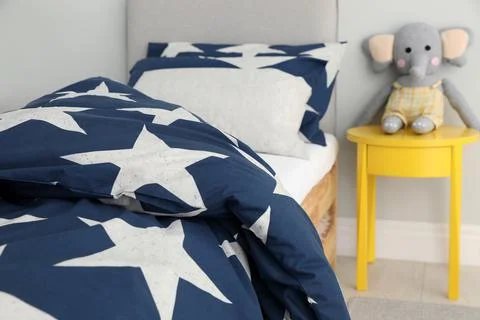 Bed with star patterned linens in child's bedroom. Interior design Stock Photos