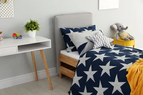 Bed with star patterned linens in child's bedroom. Interior design Stock Photos