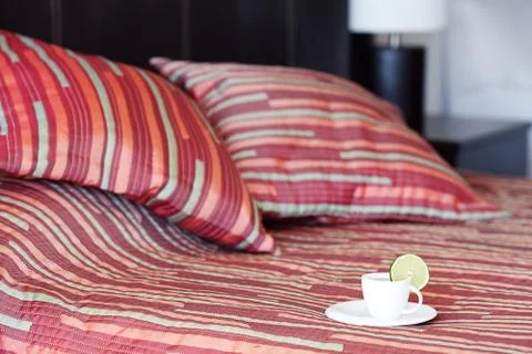 Bed with two pillows, a cup of tea on the blanket Stock Photos