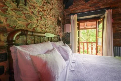 A bed with two pillows illuminated by the light of a large window Stock Photos