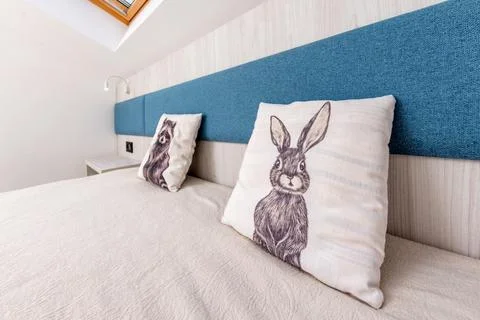 A bed with two pillows, one of which has a rabbit on it Stock Photos