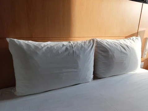 A bed with two pillows on top of it next to a wooden headboard Stock Photos