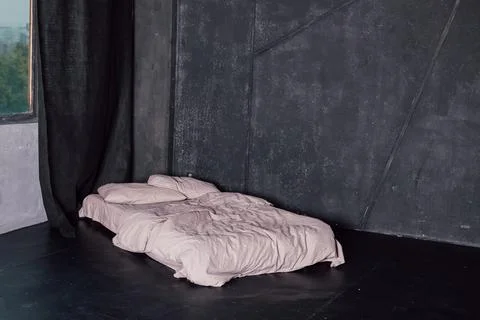 Bed with white bed standing in a dark room near the window Stock Photos