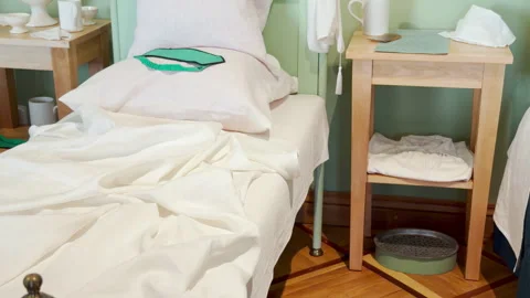 A bed with white sheets and slippers rests on a parquet floor Stock Footage 344974849