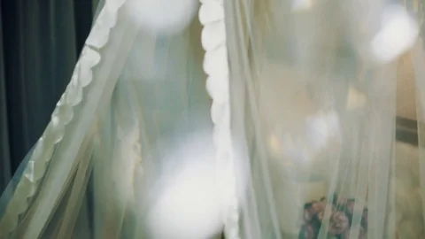 Bed with white silk transparent veil beyond glass chandelier particles Stock Footage